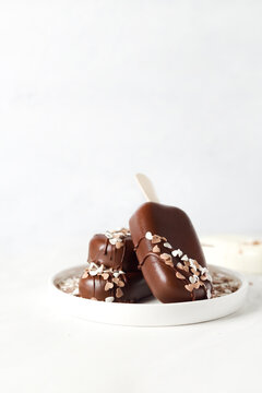 Chocolate cakesicles decorated with heart sprinkles on a white plate
