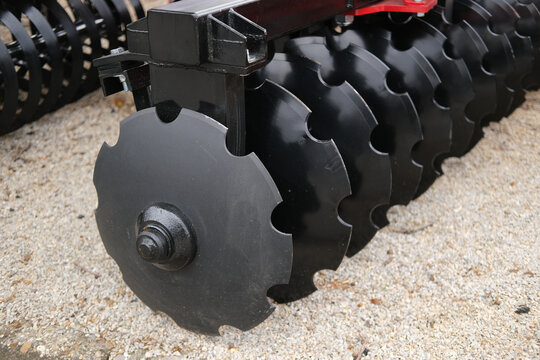 Close up of disc harrow machinery with round metal discs and bolts for soil tillage in agriculture and farming fields
