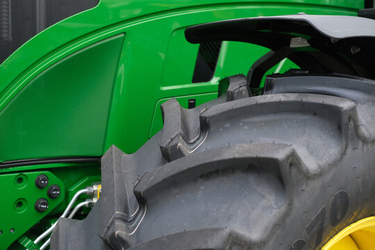 Close up of a green tractor with large tire, highlighting rugged farm machinery and agricultural equipment used for farming tasks in fields during harvest season.