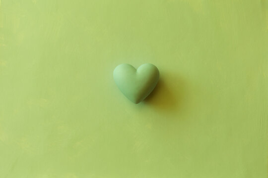 green volumetric heart on plain background. Monochrome background with copy space for Valentine's Day and holiday of love