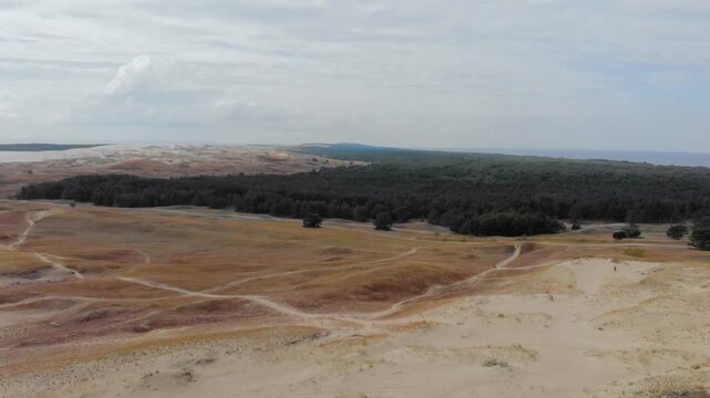 An expansive aerial shot captures the impressive Parnidis Dune landscape and dark forest on the Curonian Spit, near Nida, Lithuania.