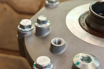 Obraz premium Close up macro view of industrial metallic wheel hub with steel bolt and thread showing mechanical engineering precision detail reflecting strength and reliability in automotive machinery part