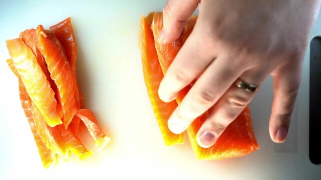 A professional close-up of a chef slicing a fresh salmon fillet on a white cutting board, showcasing culinary precision and the vibrant, healthy texture of the raw fish.
