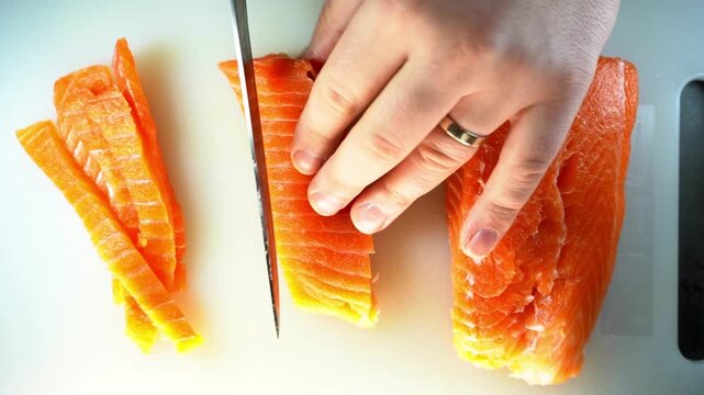 A professional close-up of a chef slicing a fresh salmon fillet on a white cutting board, showcasing culinary precision and the vibrant, healthy texture of the raw fish.