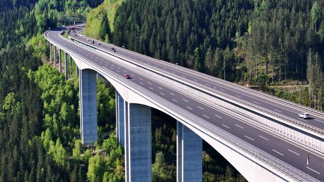Aerial view of the Lavanttal Bridge viaduct spanning across a deep valley with dense green forests and cars driving on the highway Wolfsberg, Carinthia, Austria.