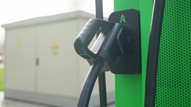 Electric charging cable connected to outdoor green EV station