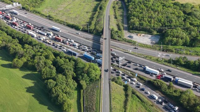 An aerial perspective shows a long line of cars and trucks completely stopped on a multi-lane highway and its intersecting roads.