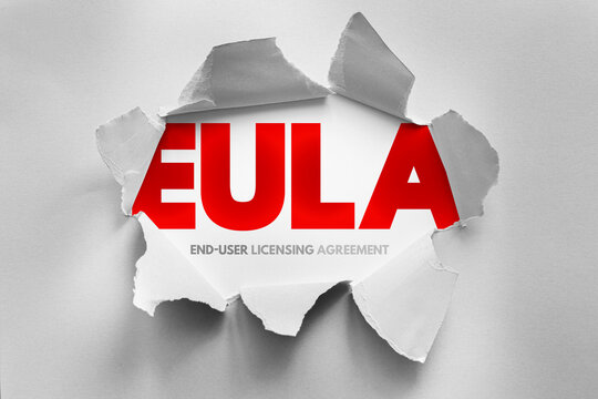 EULA end user licensing agreement text shown through torn paper surface, software legal concept describing usage terms, permissions, compliance rules and digital agreement structure