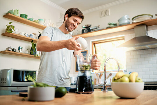 Earphones, man and yogurt in blender in home for green smoothie, healthy diet or detox shake. Music, happy person or meal prep with ingredients in kitchen for breakfast drink, nutrition or gut health