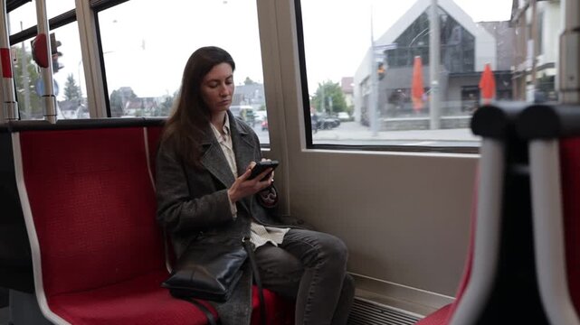 Woman using smartphone while commuting on public transport with passing scenery