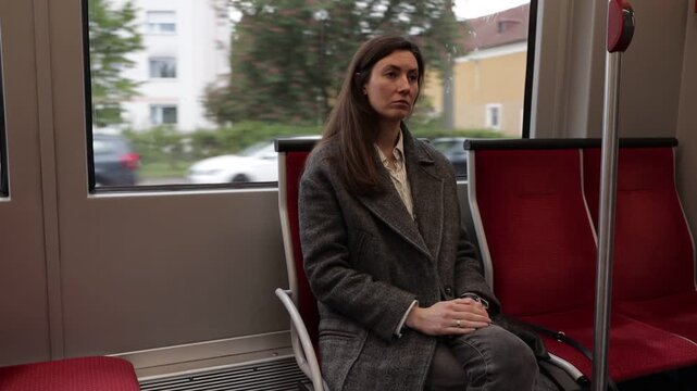 Woman riding public transport looking out window at passing city scenery