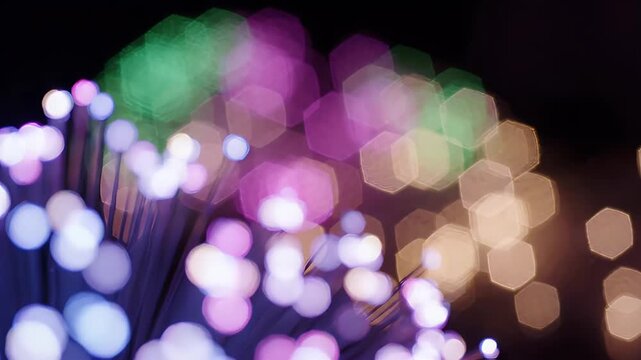 Abstract bokeh lights and optical fiber strands creating a vibrant and colorful light show in the dark