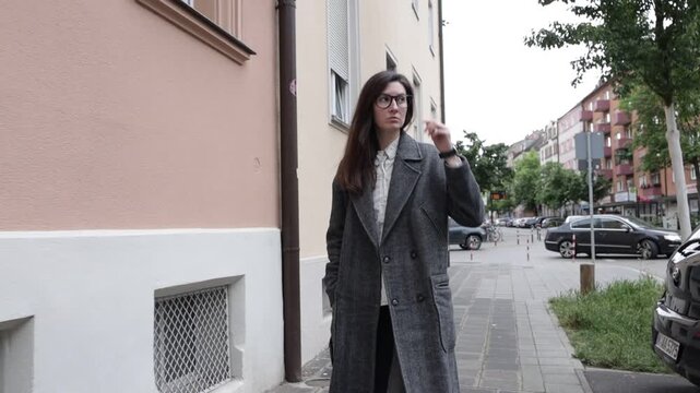 Woman in coat walking on sidewalk in European city street