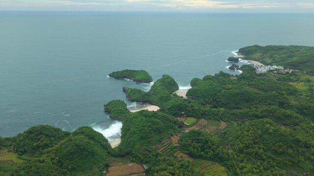 Aerial view of Sedahan Beach with lush green cliffs and white sand coves in Girisubo, Special Region of Yogyakarta, Indonesia.