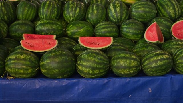 Man choosing sliced watermelon at busy local street market authentic bazaar shopping experience realistic everyday food culture and summer lifestyle