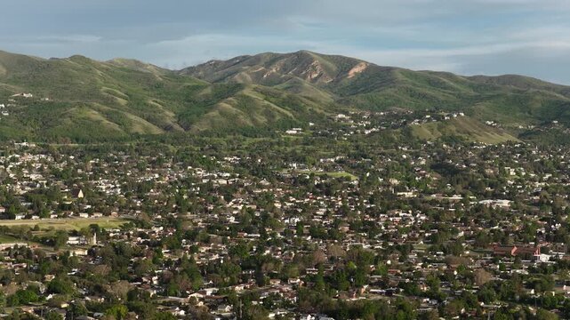 Wide aerial of Wasatch Mountain Range and Bountiful Utah homes in foothills on sunny spring day
