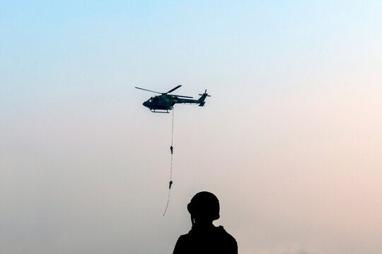 Silhouette military man looking para commandos conduct high-stakes slithering i.e. fast-roping and rappelling from helicopters for rapid insertion into inaccessible areas.
