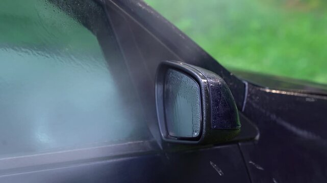 Washing car mirror with pressure washer outdoors. High pressure car wash. Car wash