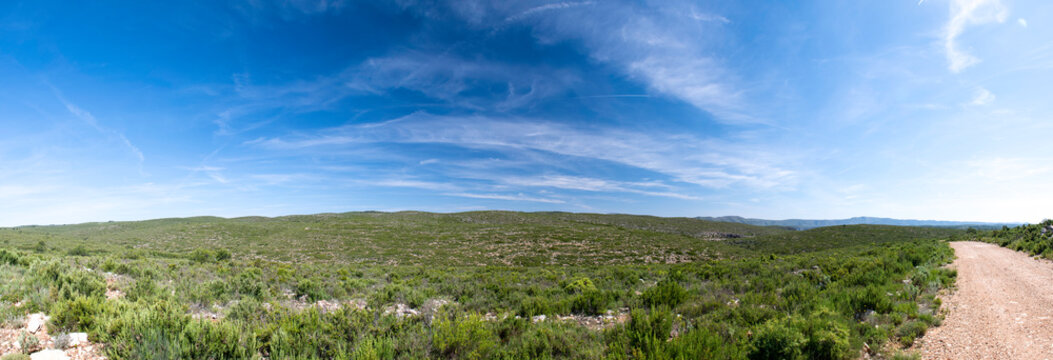 Fotograf&iacute;a panor&aacute;mica de monta&ntilde;a un d&iacute;a con el cielo azul turquesa y nubes blancas.