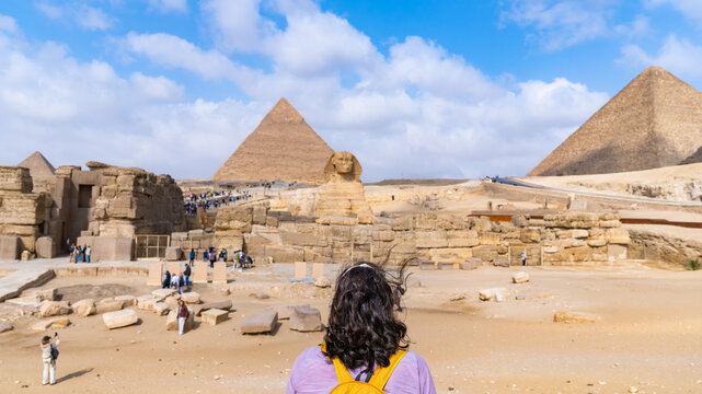 Woman traveler viewing the iconic great sphinx and vast pyramid complex, an ancient marvel attracting global tourism, in Giza, Egypt