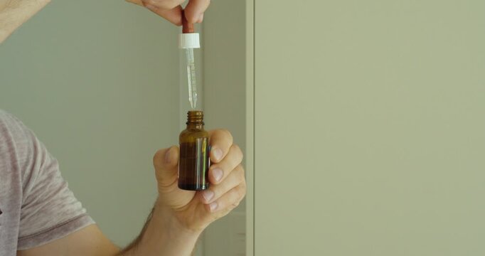 holding a small amber bottle and using a pipette to collect liquid drops. Suitable for vitamins, supplements, medication, dosage, healthcare, wellness, pharmaceutical, and natural remedy concepts.