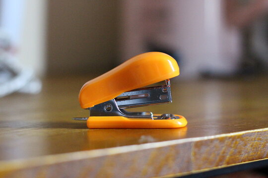 Orange stapler on wooden table