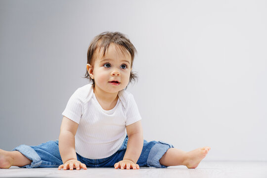 A sweet little girl is doing the splits on the floor. Healthy development in children.