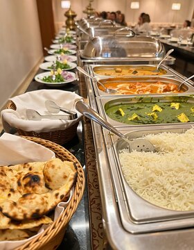 Indian Buffet Line with Naan Bread and Curry Dishes.