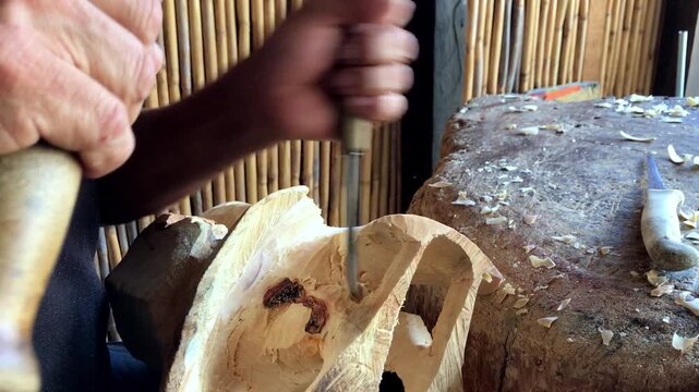 Close view of artisan carving wooden sculpture with hand tools and detailed craftsmanship inside rustic traditional workshop in Mexico