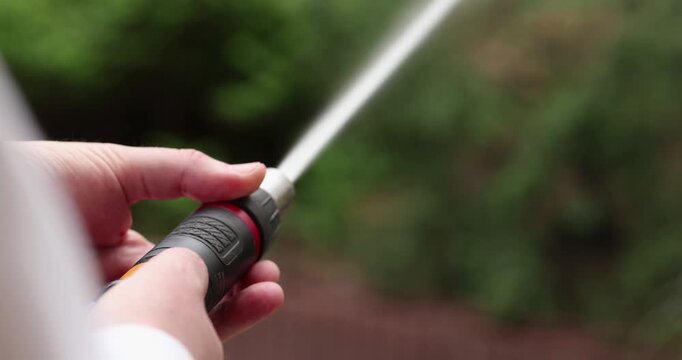 Close-up view when a person demonstrating a garden hose nozzle during spraying water in different and specific modes.