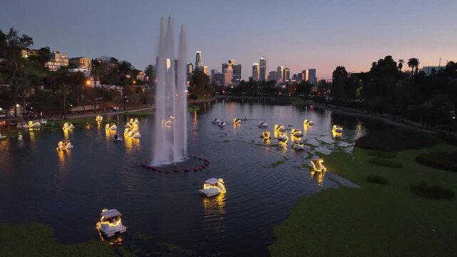 Aerial slow rise view of swans at Echo Park Lake and downtown Los Angeles Skyline