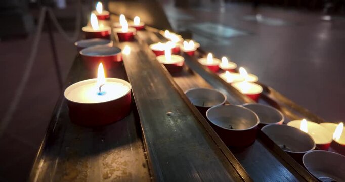 Close-up zoom of lit prayer candles inside Santa Maria del Fiore in Florence, Italy, symbolizing faith, devotion and personal petitions within the Catholic tradition.