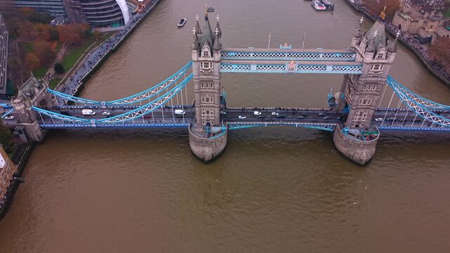The iconic Tower Bridge in London is a vehicular and pedestrian bridge that crosses the River Thames - tilt down aerial sliding during autumn
