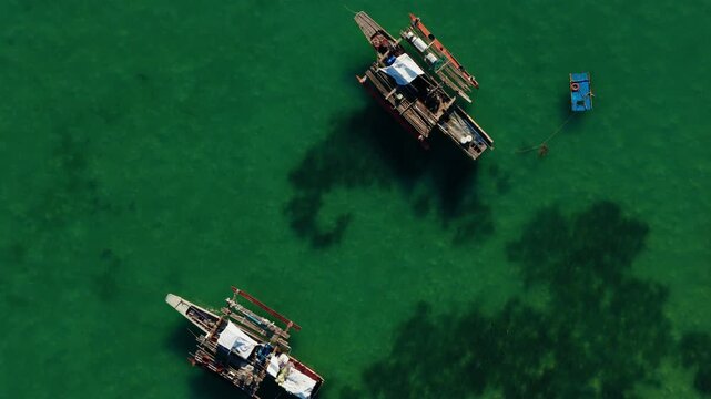 Traditional outrigger boat floating on clear green water in Bohol, drone top down backdrop