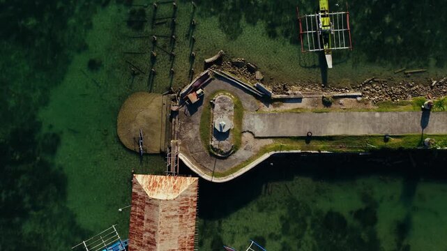 Stone pier and coastal walkway beside Dauis Church in Bohol, drone top down ascend at early morning
