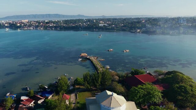 Dauis Church rooftop beside calm coastal waters in Bohol Philippines, drone dolly to pier