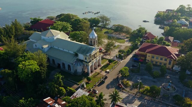 Side view of Dauis Church near tropical waterfront in Bohol Philippines, drone orbit reveal