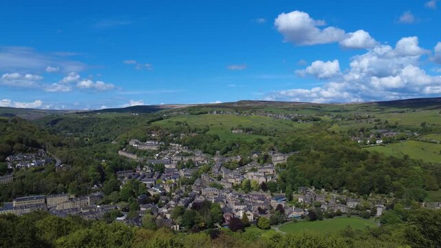 High panoramic aerial view of the town of Hebden Bridge surrounded by Fields and Meadows with a blue cloudy sky
