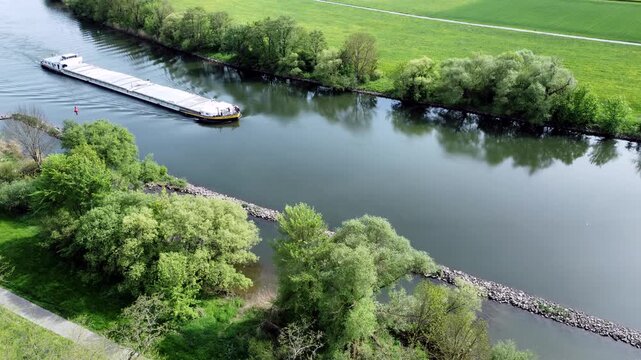 Drohne fliegt &uuml;ber Fluss mit Binnenschiff, Ufer mit Auwald und Agrarland, Luftaufnahme