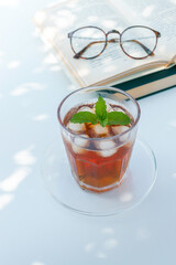 Iced tea with mint and glasses on an open book in soft natural light © 清美 小池