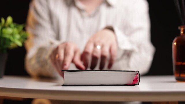 Person's hands interacting with a book on a table with decorative elements