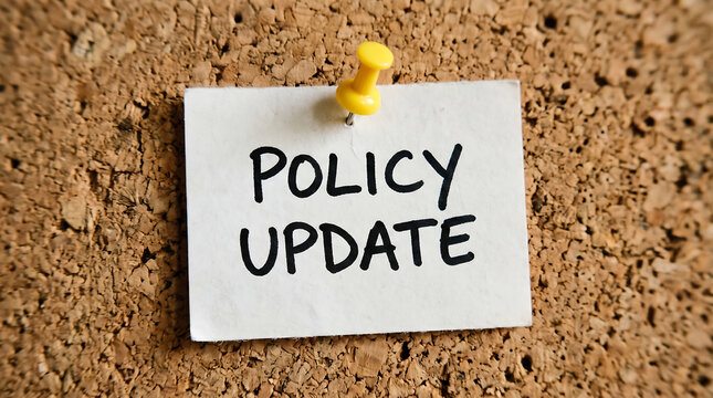 Policy Update handwritten note on white paper, corporate announcement pinned to cork board, business regulation change message with yellow pushpin