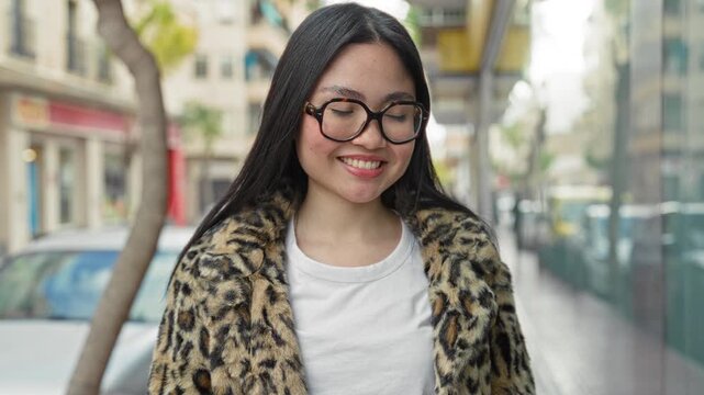 Woman adjusting glasses with hand in hair on street wearing leopard coat and white shirt; calm confidence.