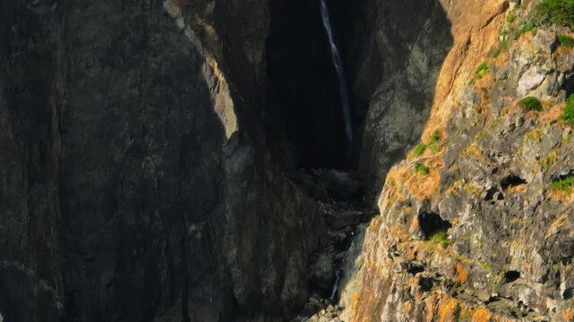 A Serene and Elegant Waterfall Trickling Down a Towering, Dark Volcanic Gorge Bathed in Golden Sunset Light, Flores Island, Azores
