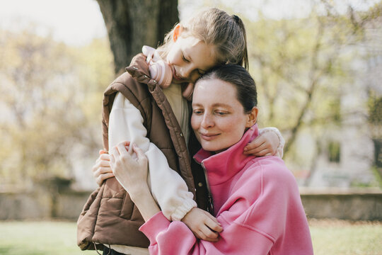 Happy mother and daughter relaxing in a park on sunny day.