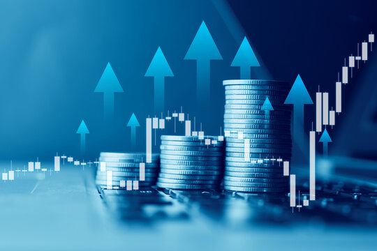 Financial growth and stock market investment concept. Growing stacks of coins on laptop keyboard with rising charts and blue upward arrows overlay