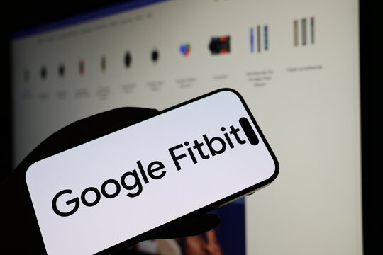Kiel, Germany - 05-20-2026: Smartphone displaying US wearable technology company Google Fitbit logo in front of companys webpage