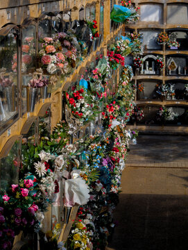 Nichos en un cementerio con ramos de flores