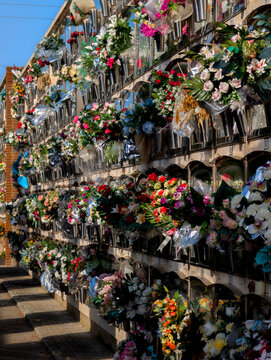 Nichos en un cementerio con ramos de flores