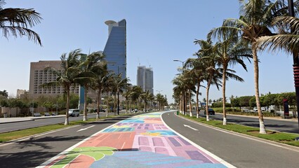 Fototapeta premium Bright street art on Jeddah waterfront walkway with palm trees and modern skyscrapers in jeddah saudi arabia